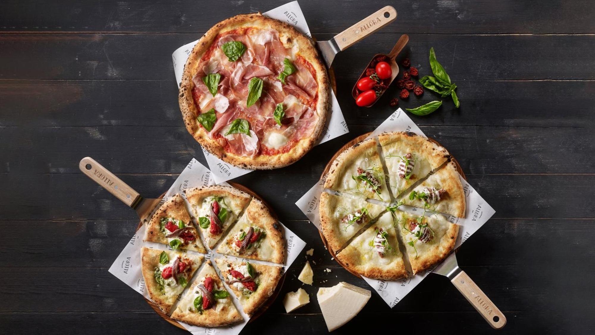 Crowne Plaza Changi Airport By Ihg Singapur Exterior foto The photo depicts three different types of pizzas on wooden serving paddles. 

1. **Top Pizza**: This pizza features a combination of thinly sliced cured meats, likely prosciutto, alongside fresh basil leaves and mozzarella cheese on a light-colored 