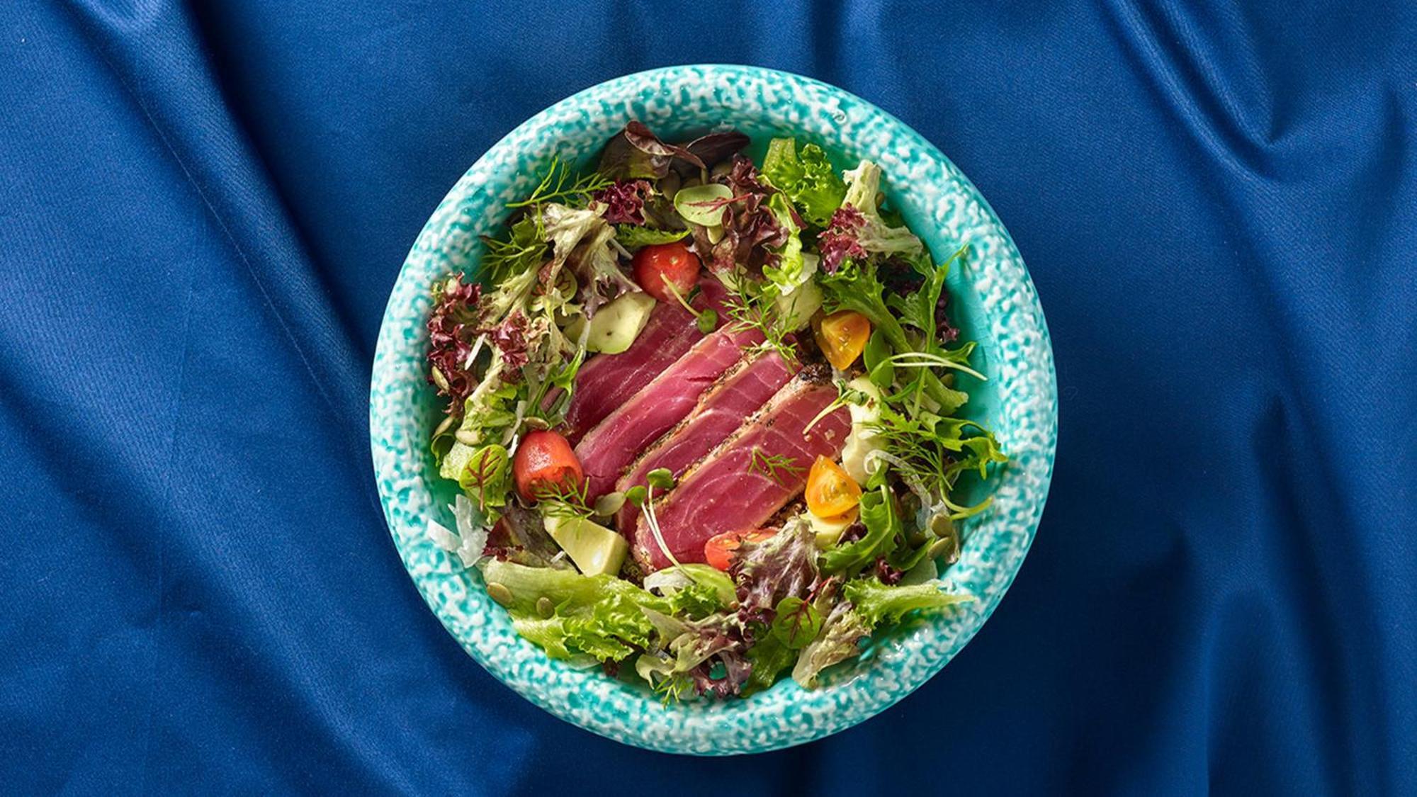 Crowne Plaza Changi Airport By Ihg Singapur Exterior foto The photo shows a bowl of salad featuring a variety of fresh leafy greens, including different types of lettuce. There are sliced pieces of seared tuna placed over the salad, adding a protein element. The salad is garnished with cherry tomatoes and p