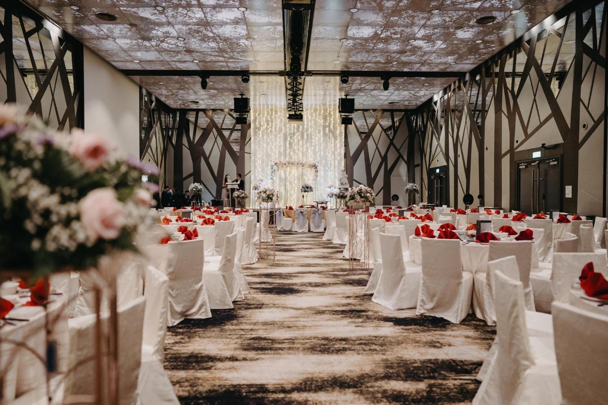 Crowne Plaza Changi Airport By Ihg Singapur Exterior foto The photo shows an elegantly decorated banquet hall set up for an event, likely a wedding or formal gathering. The room features rows of tables covered in white tablecloths, each adorned with vibrant red flowers. There are also floral arrangements on