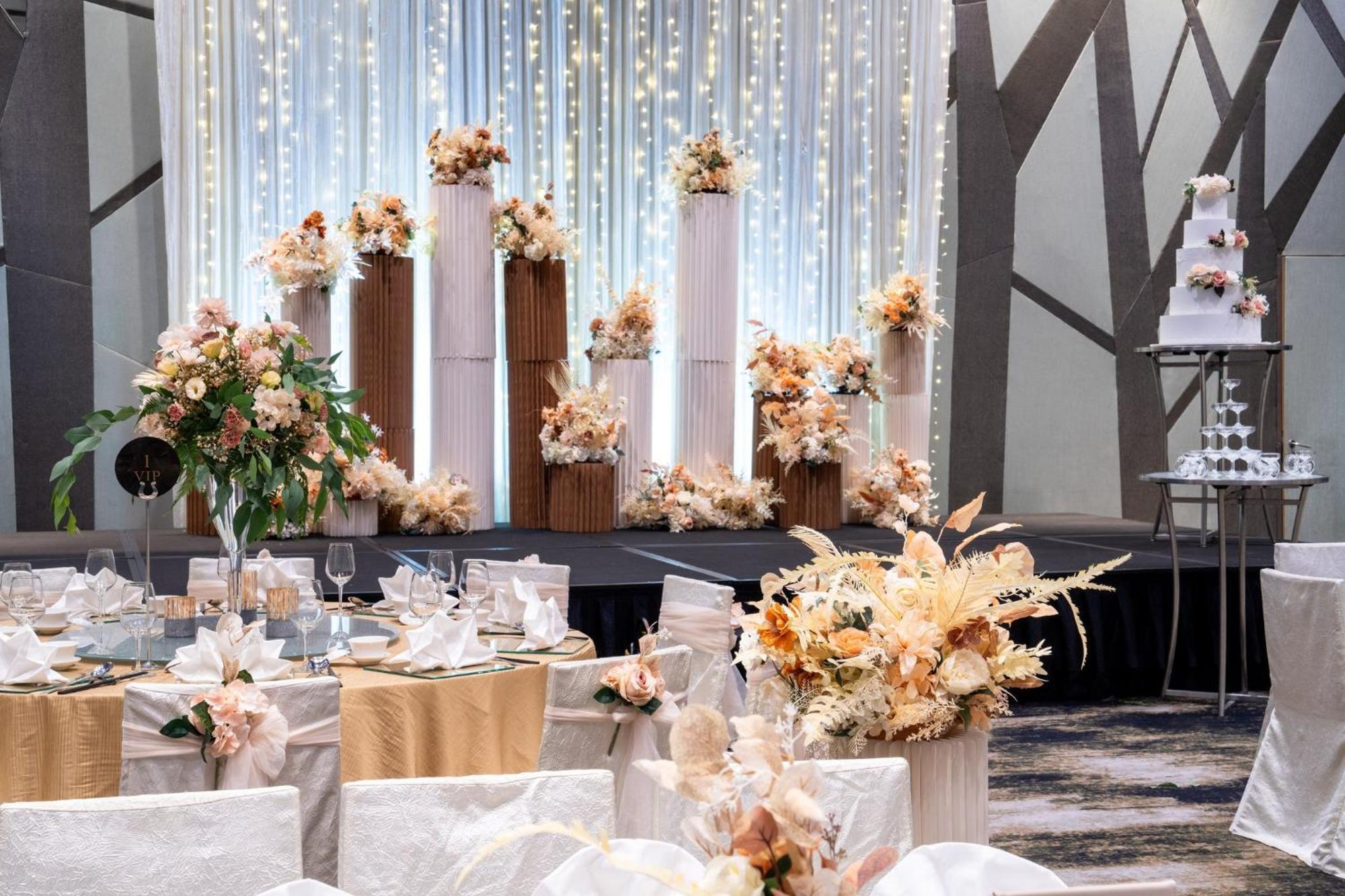 Crowne Plaza Changi Airport By Ihg Singapur Exterior foto The photo shows an elegantly decorated wedding reception. In the background, there are tall columns adorned with floral arrangements in soft, pastel colors. These floral displays are complemented by string lights hanging above, creating a romantic am
