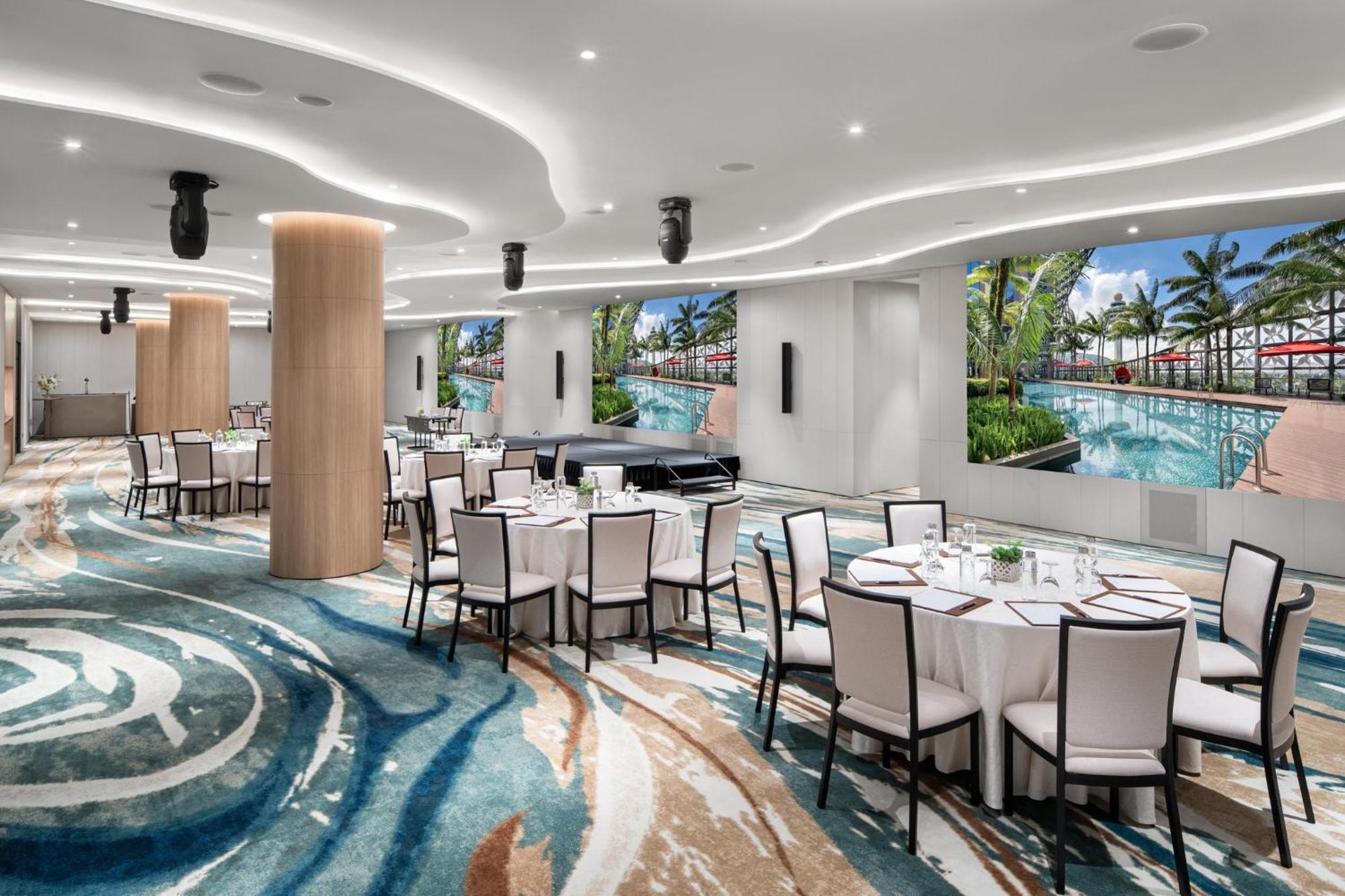 Crowne Plaza Changi Airport By Ihg Singapur Exterior foto The photo showcases a modern event space or dining area. It features several round tables covered with white tablecloths and set with dishes and utensils. The floor has an eye-catching design with swirling patterns in various shades of blue and beige